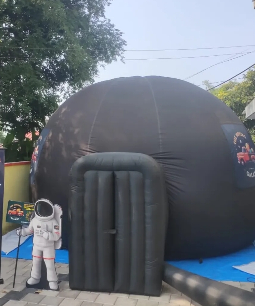 Children sitting inside the Zentroniq portable planetarium dome looking up at projected stars